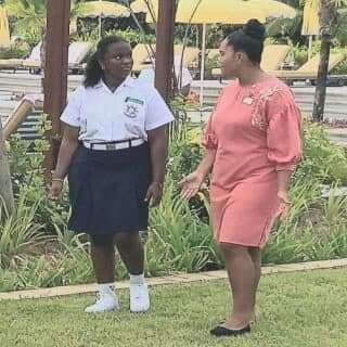 A student in school uniform talking with a hotel staff member in a garden setting.
