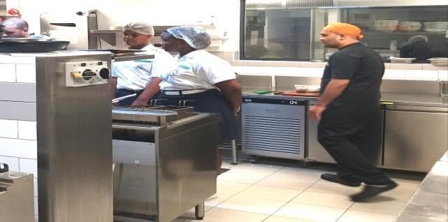 Kitchen staff at a stainless steel pass in a hotel kitchen during filming.