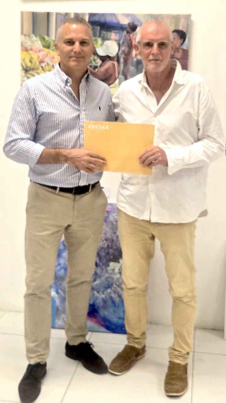 Two men in white shirts standing side by side in a gallery, holding an open document folder between them.