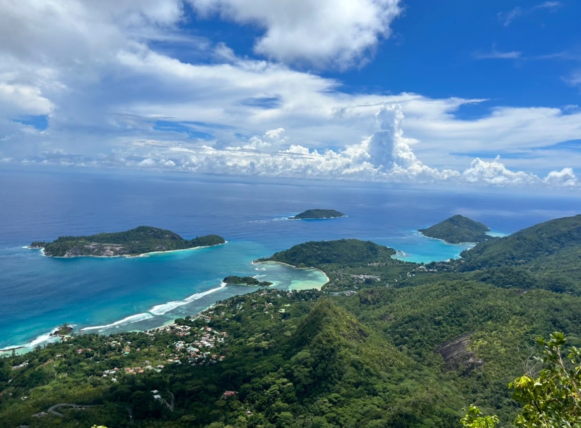 An elevated view across green islands, reefs and a forested coastline